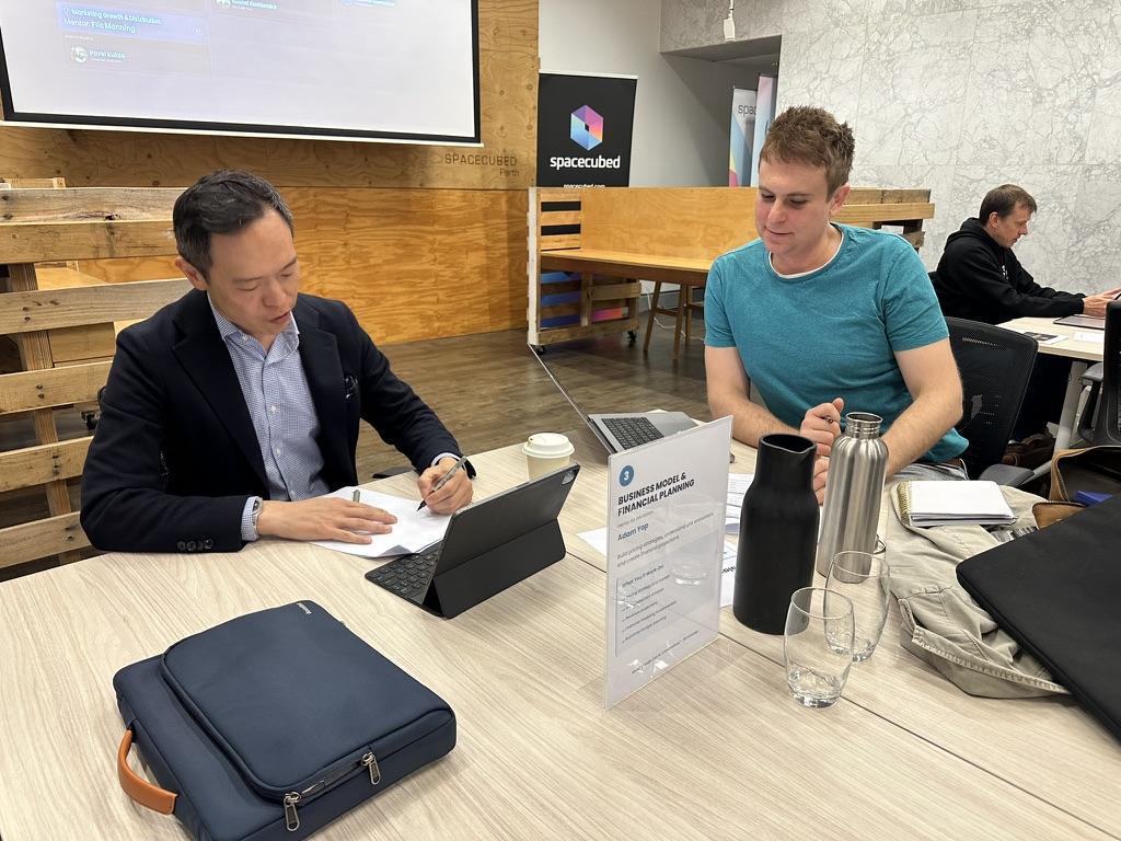 A mentor and founder in close conversation at the Business Model and Financial Planning station